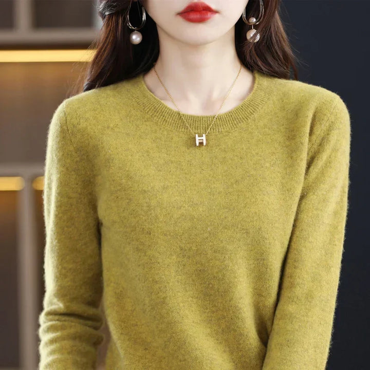 Gros plan sur un pull col rond vert olive porté par une femme, collier et boucles d'oreilles perle 1