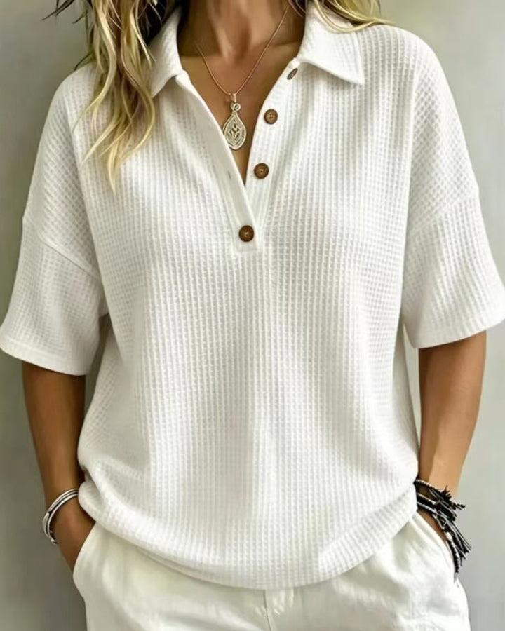 Polo blanc en maille gaufrée porté avec un pantalon blanc, col boutonné à trois boutons en bois 1