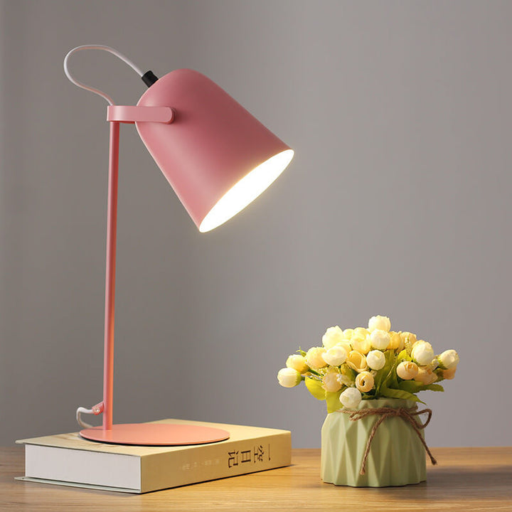 Version rose de la lampe allumée sur un livre, à côté d'un vase vert et de fleurs blanches. 8