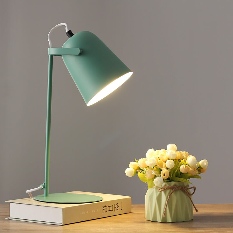 Version verte de la lampe allumée sur un livre, à côté d'un vase vert clair avec bouquet de fleurs. 9