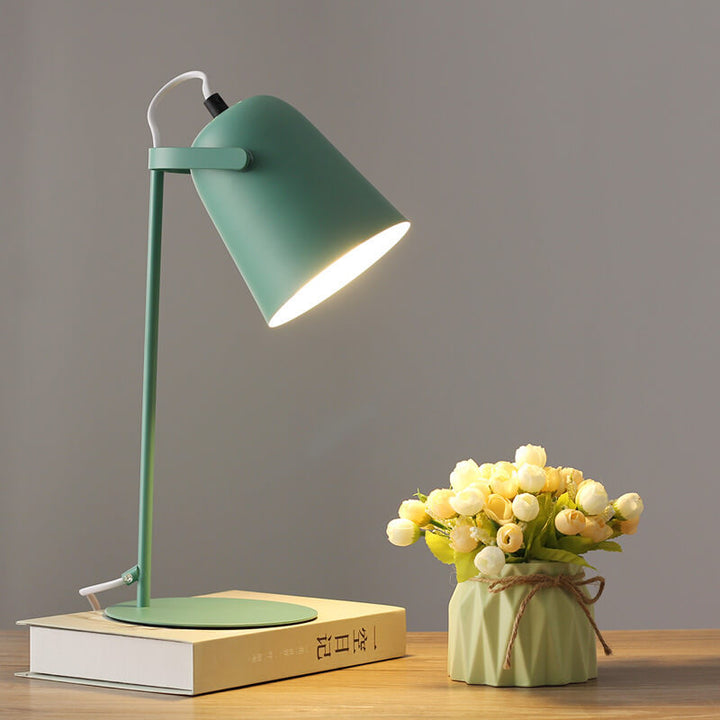 Version verte de la lampe allumée sur un livre, à côté d'un vase vert clair avec bouquet de fleurs. 9
