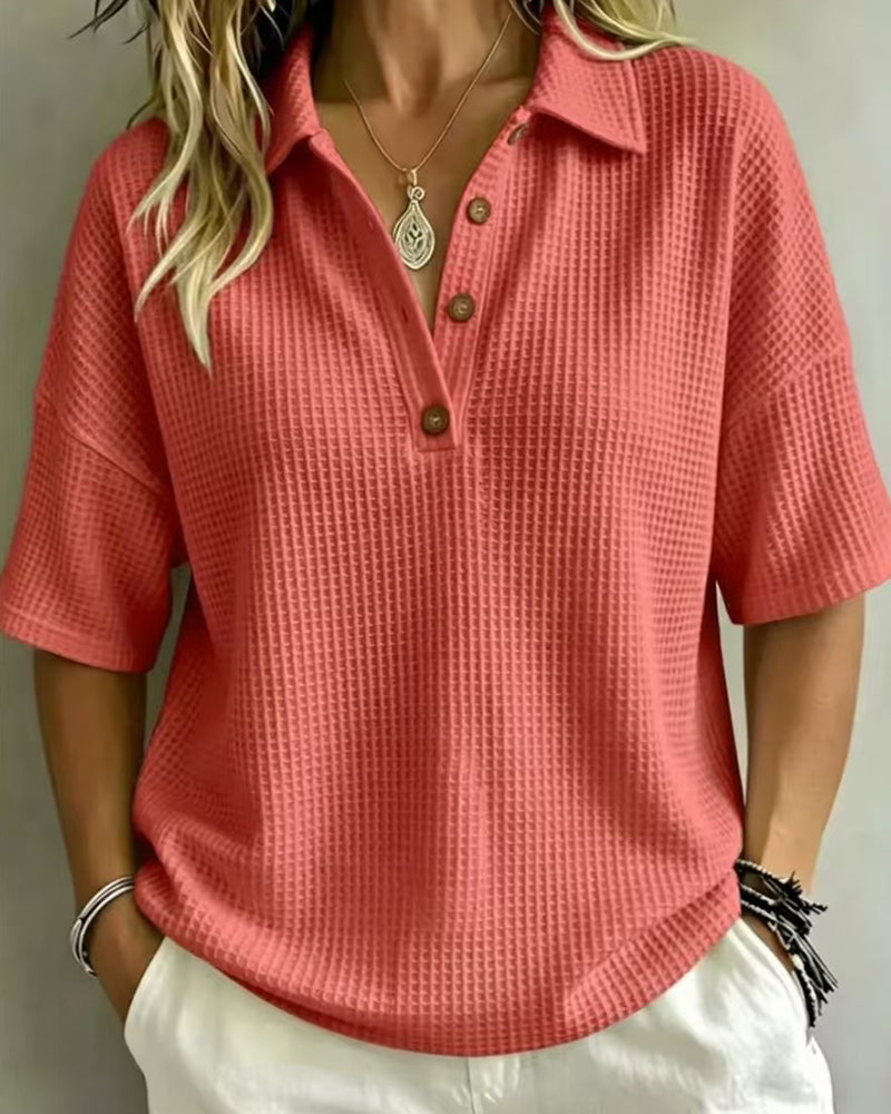 Polo corail en maille gaufrée, vue de face portée avec pantalon blanc et collier pendentif 4