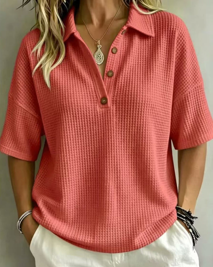 Polo corail en maille gaufrée, vue de face portée avec pantalon blanc et collier pendentif 4