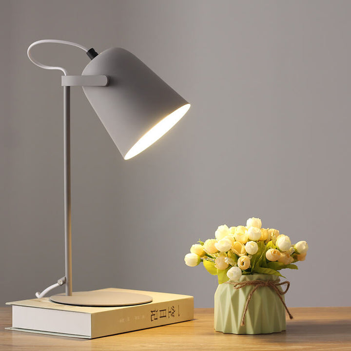 Version grise de la lampe allumée sur un livre, avec un vase vert et un bouquet de fleurs blanches. 10