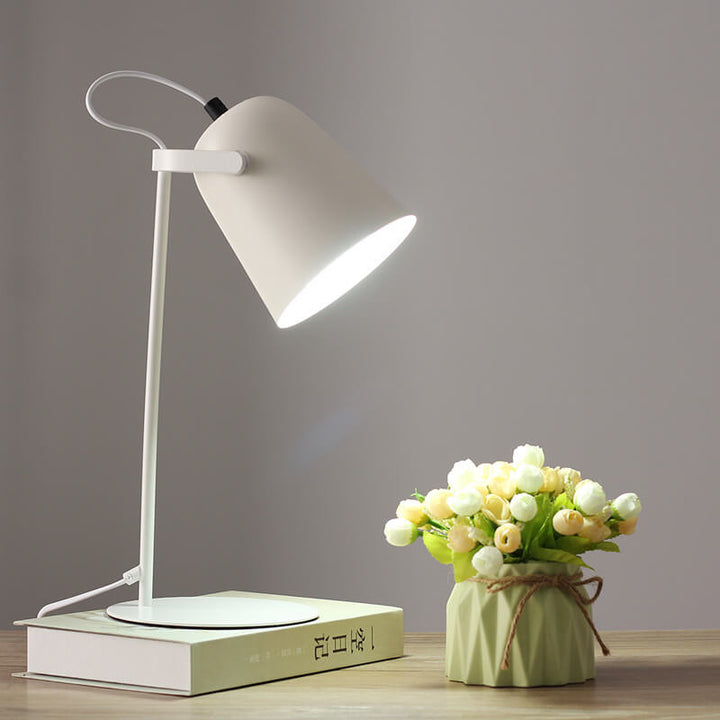 Version blanche de la lampe allumée sur un livre, près d'un vase vert clair avec bouquet de fleurs. 11