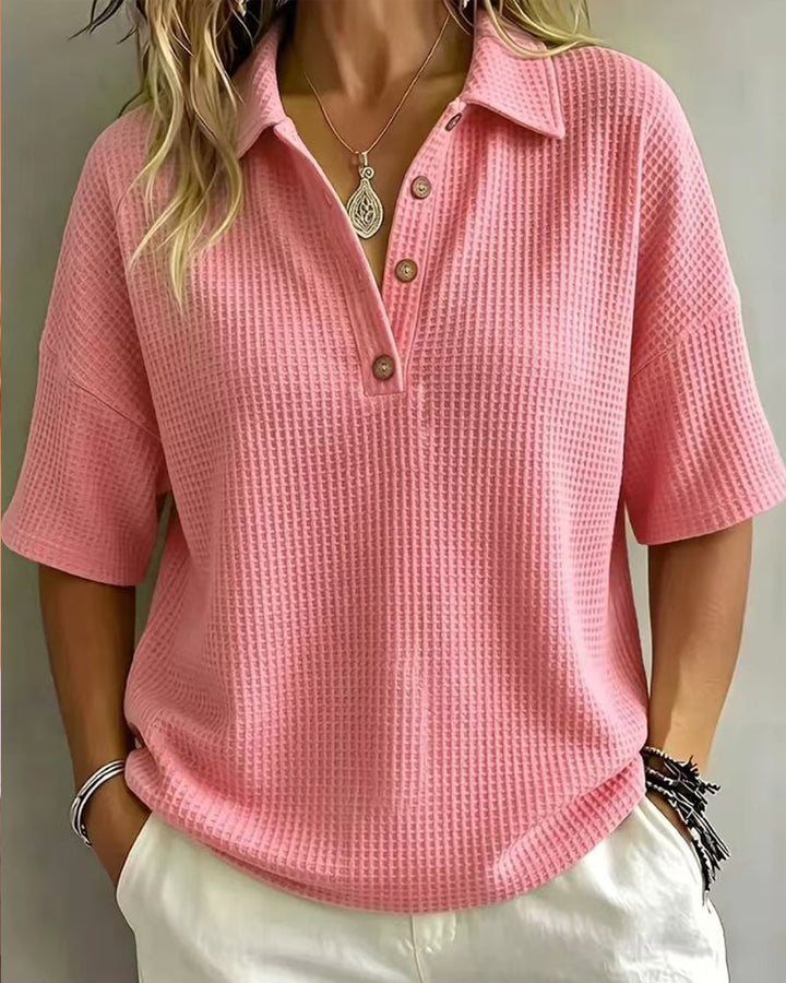 Polo rose vif en maille gaufrée, vue de face portée avec pantalon blanc 9