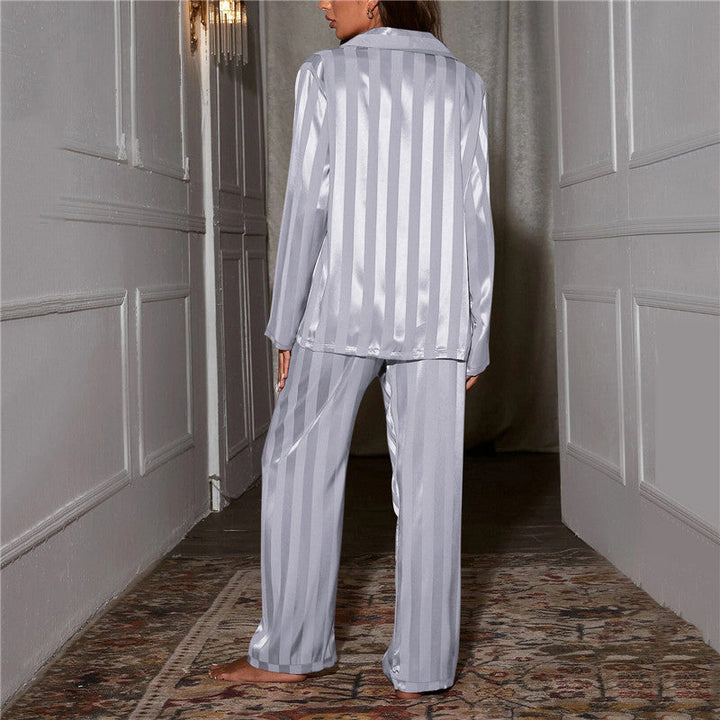 Femme vue de dos dans un couloir, pyjama satiné rayé gris clair, rayures verticales sur la chemise et le pantalon 10