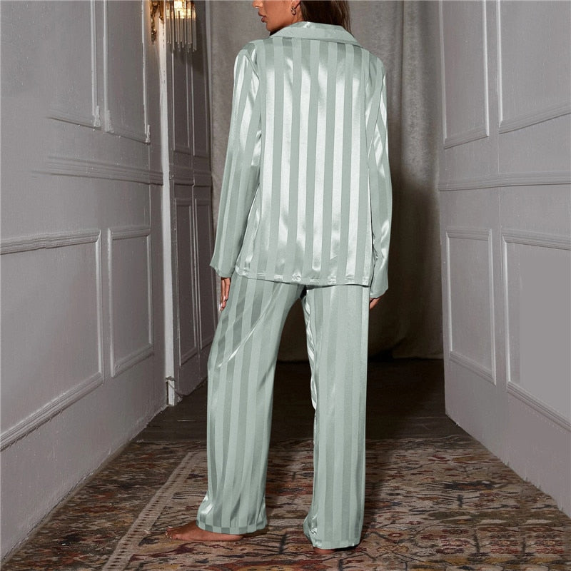 Femme vue de dos dans un couloir, pyjama satiné rayé vert d'eau, rayures verticales sur la chemise et le pantalon 13