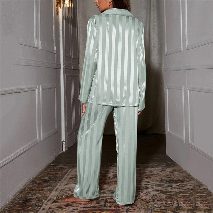 Femme vue de dos dans un couloir, pyjama satiné rayé vert d'eau, rayures verticales sur la chemise et le pantalon 13