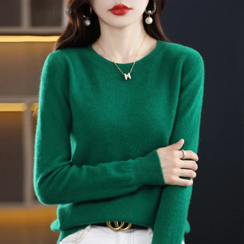 Pull col rond vert émeraude porté avec un pantalon blanc et une ceinture, bras croisé 6