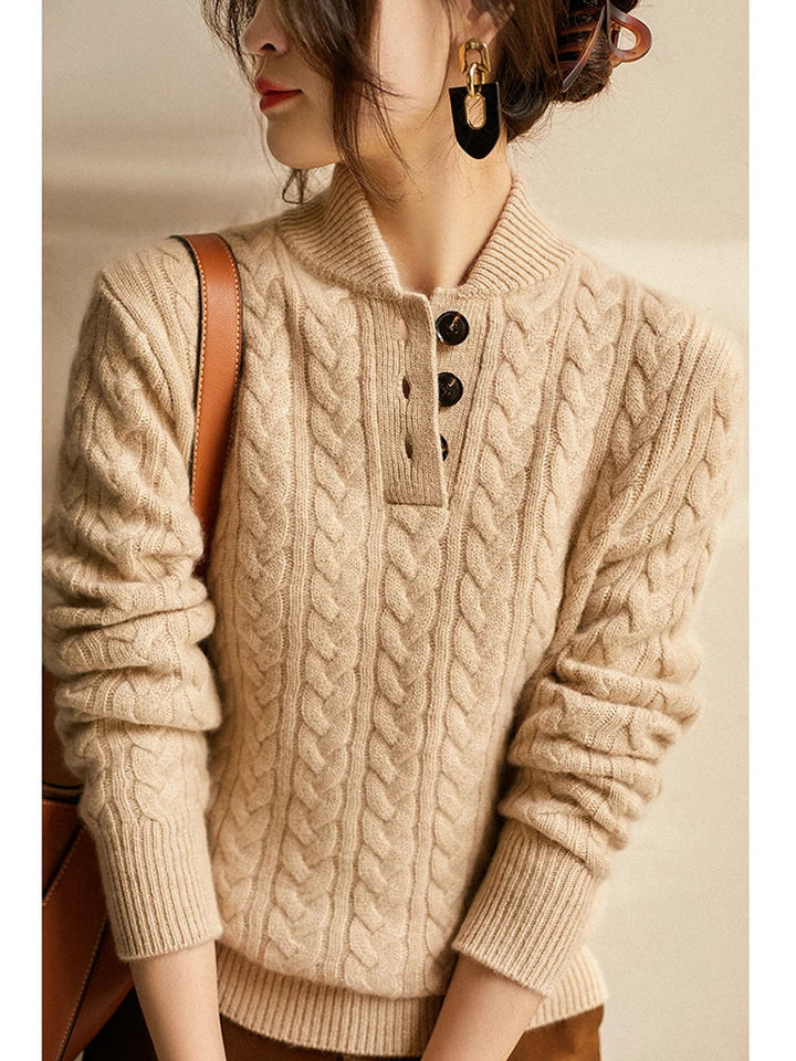 Gros plan sur le haut du pull beige torsadé, col et trois boutons visibles, boucles d'oreilles et sac en cuir sur l'épaule. 11