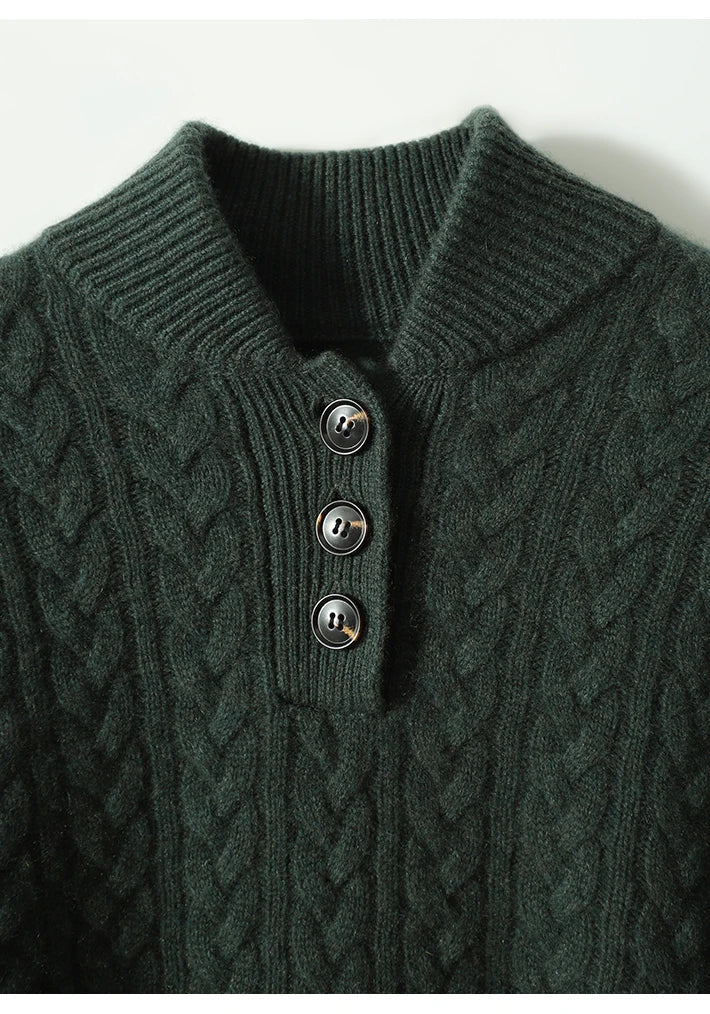 Gros plan sur le col et les trois boutons façon corne du pull vert foncé à torsades, bords côtelés visibles. 19
