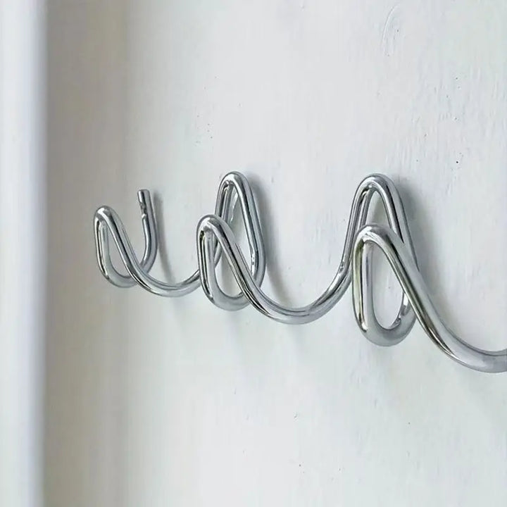 Gros plan de côté sur le portant en métal chromé brillant, avec ses boucles ondulées fixées à un mur blanc. 6