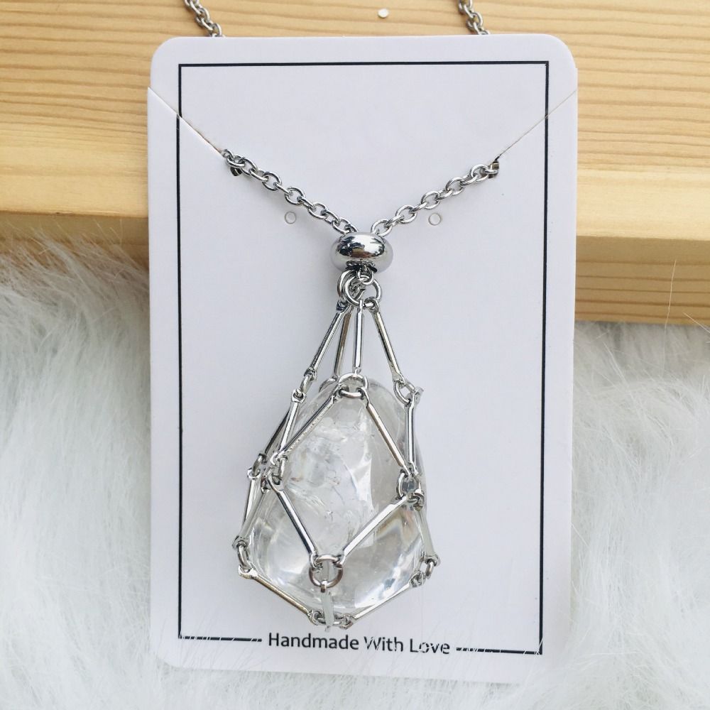 Collier argenté avec filet autour d'une pierre de cristal transparent en goutte, présenté sur une carte blanche posée sur du bois. 15
