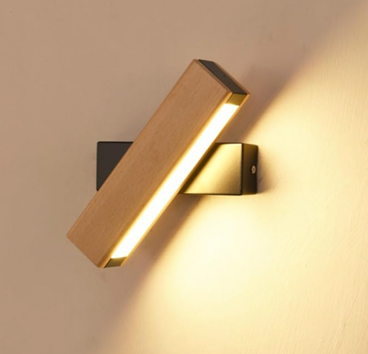 Gros plan sur l'applique à support noir, barre en bois inclinée et bande LED qui éclaire le mur. 7