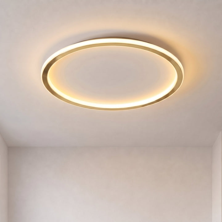 Plafonnier en anneau doré allumé, lumière chaude, vu de face sur un plafond blanc 1