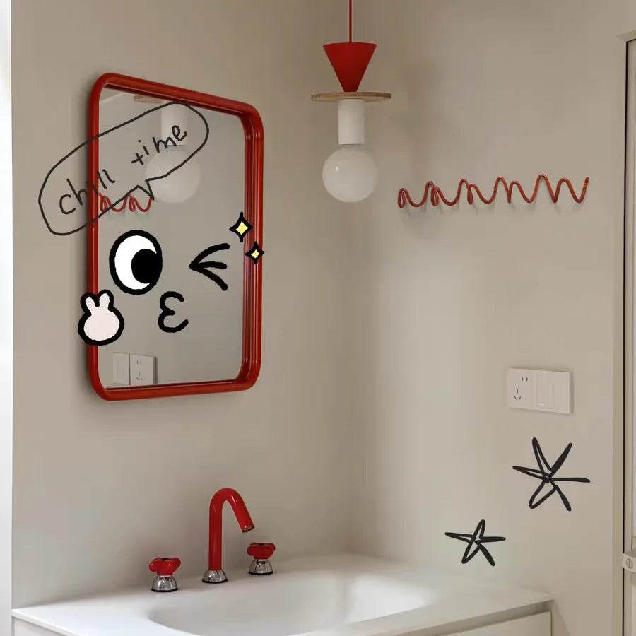 Portant rouge ondulé vide fixé près d'un miroir rouge à cadre arrondi, dans une salle de bains décorée de dessins. 4