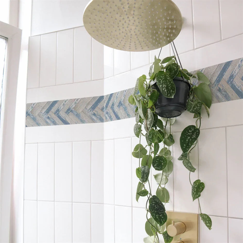Frise à chevrons bleu et blanc usé sur des carreaux blancs de douche, avec une plante suspendue 8