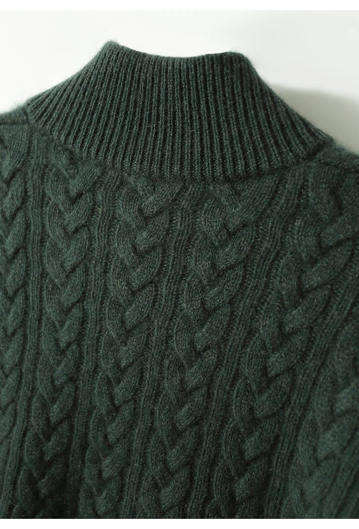 Gros plan sur le col montant côtelé et les torsades du tricot, en vert foncé, vus de près. 21