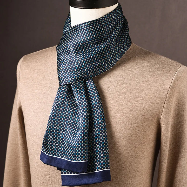 Foulard en soie bleu marine à petits carrés blancs et turquoise, liséré blanc en bordure, porté sur un mannequin en pull beige. 24