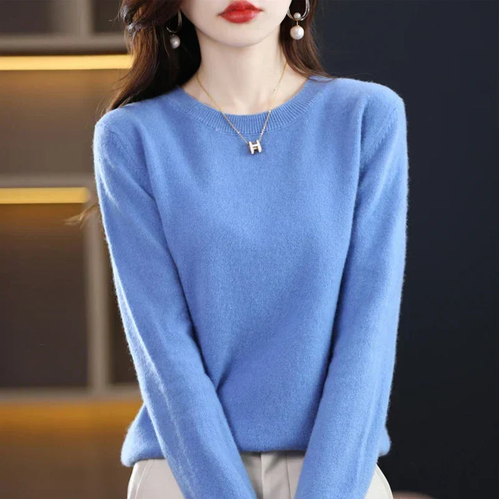 Pull à col rond bleu ciel porté par une femme, avec collier doré et boucles d'oreilles perle 22