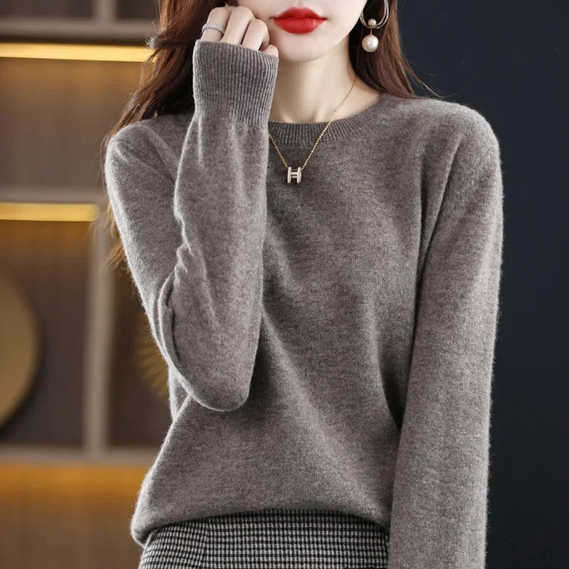 Pull à col rond gris-brun porté par une femme, avec collier doré et jupe à carreaux 21