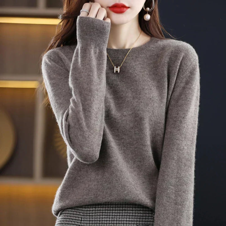 Pull à col rond gris-brun porté par une femme, avec collier doré et jupe à carreaux 21