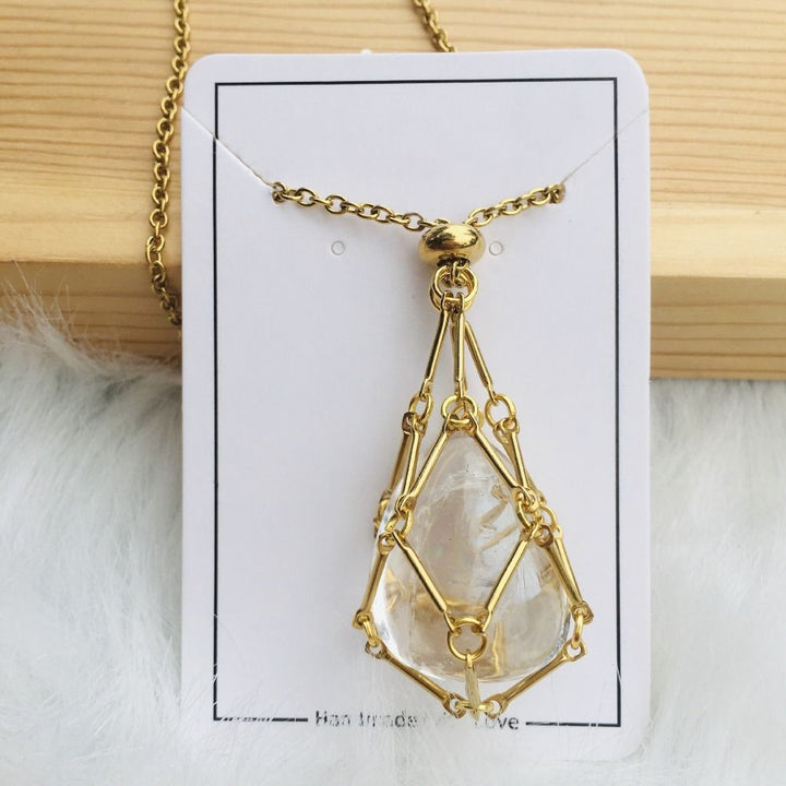 Collier doré dont le filet retient une pierre transparente en forme de goutte, présenté sur une carte blanche. 14