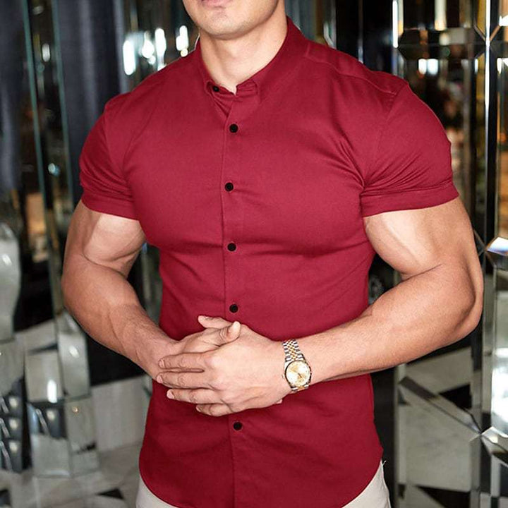 Chemise rouge bordeaux à boutons noirs, portée par un homme musclé aux mains jointes, avec une montre dorée. 4