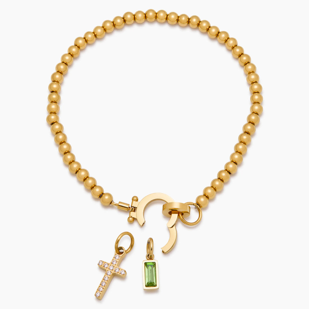 Bracelet doré à perles posé à plat, fermoir ouvert, avec la croix sertie de strass et la pierre verte détachées. 7