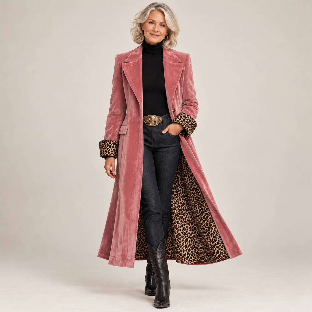 Femme aux cheveux blonds portant le manteau rose en velours ouvert sur un pull noir, un jean et des bottes de cowboy, sur fond uni. 1