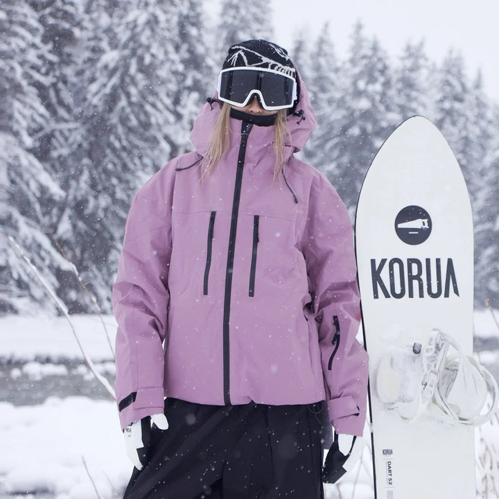 Veste rose mauve avec fermetures éclair noires, portée devant une forêt sous la neige, une personne tenant un snowboard blanc à ses côtés. 3