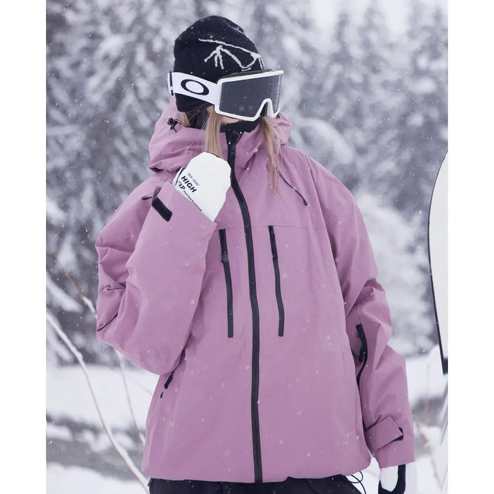 Gros plan de trois quarts sur la veste rose mauve, poches zippées sur la poitrine et capuche relevée, sous les flocons. 4