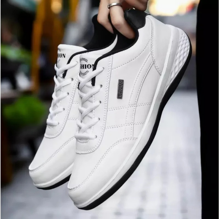 Paire de baskets blanches à lacets et semelle blanche et noire, tenue à la main dans une rue. 4
