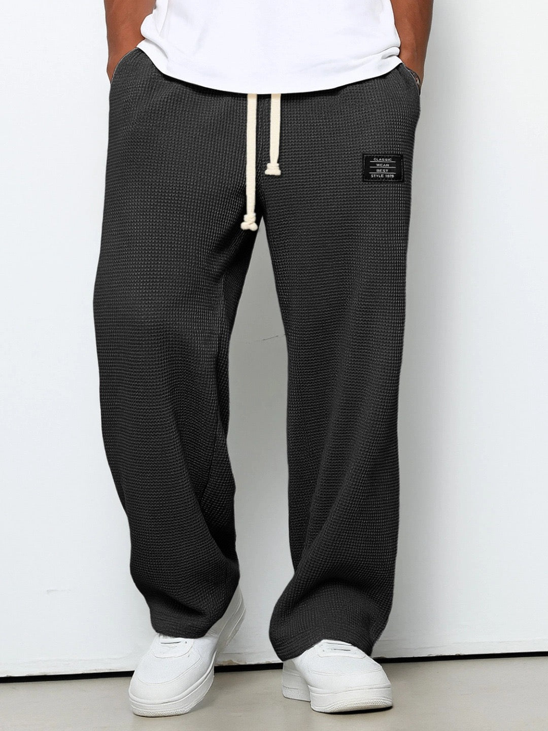 Pantalon large gris anthracite en maille gaufrée, cordon beige à la taille, porté avec un t-shirt blanc et des baskets blanches. 1
