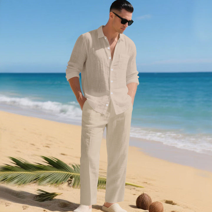 Modèle masculin sur une plage tropicale portant la chemise et le pantalon assortis en beige clair. 4