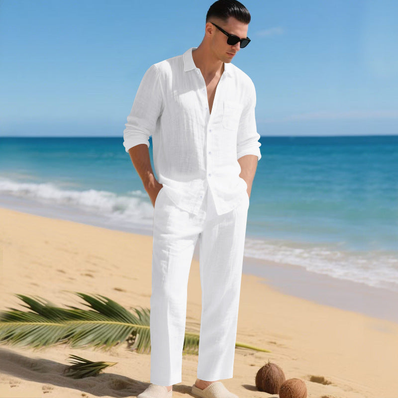 Homme sur une plage ensoleillée vêtu de l'ensemble chemise et pantalon entièrement blancs, mains dans les poches. 8