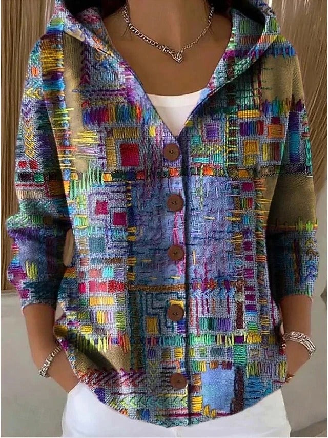 Cardigan à capuche porté par une femme, motif patchwork multicolore façon broderie en bleu, violet, vert et orange, boutons en bois. 1