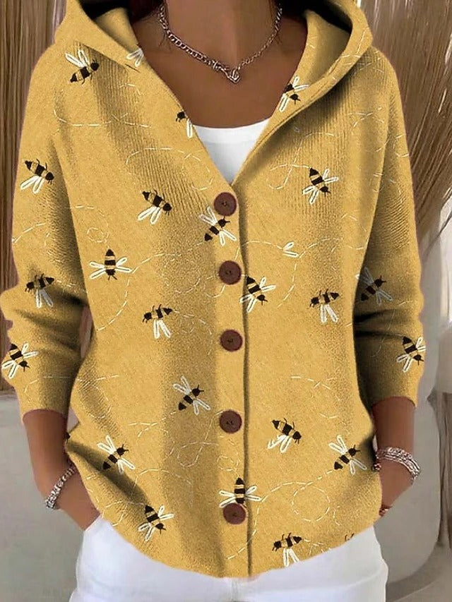 Cardigan à capuche jaune moutarde porté par une femme, orné de petites abeilles et de traits pointillés, boutons en bois marron. 2