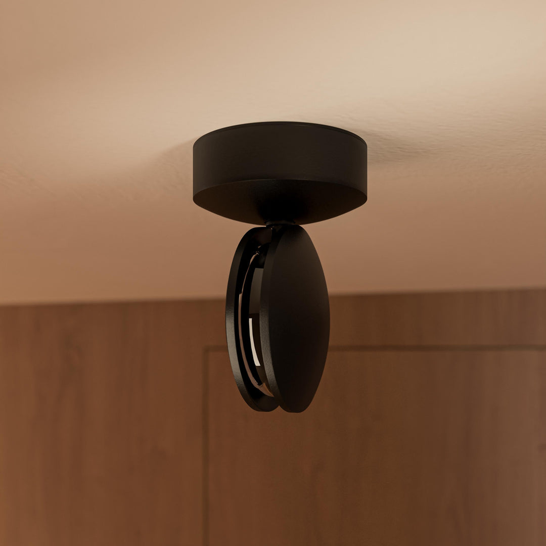 Applique noire au plafond vue de près, tête inclinée montrant la fente lumineuse et les deux disques superposés. 13