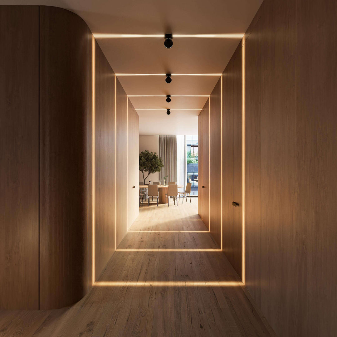Perspective frontale d'un couloir en bois avec quatre appliques noires créant des bandes de lumière sur les murs et le parquet. 16
