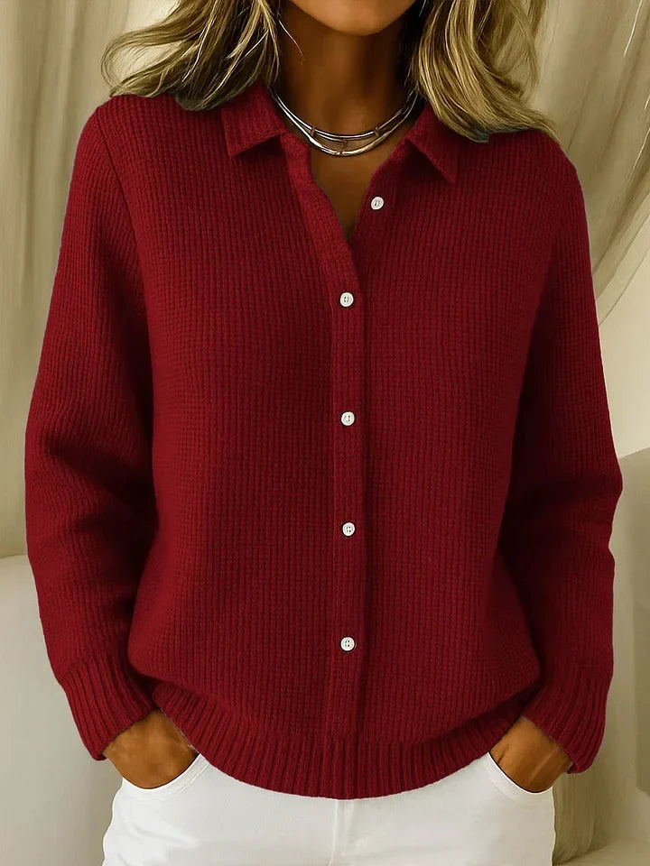 Pull en maille texturée coloris rouge bordeaux, porté avec un pantalon blanc et un collier argenté, boutons blancs sur le devant. 3