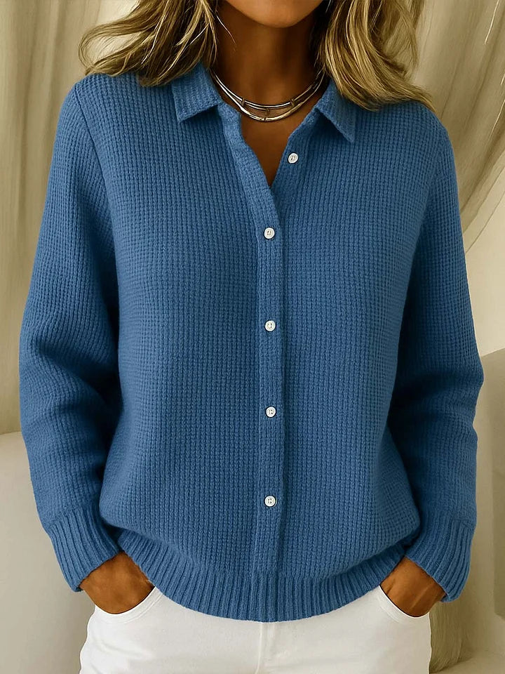 Pull en maille texturée coloris bleu denim, porté avec un pantalon blanc, col polo et rangée de boutons blancs. 4