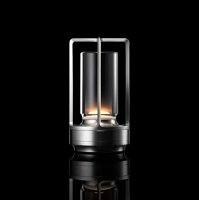 Lampe cylindrique à cadre ouvert et base argentés, allumée sur fond noir avec reflet au sol. 10