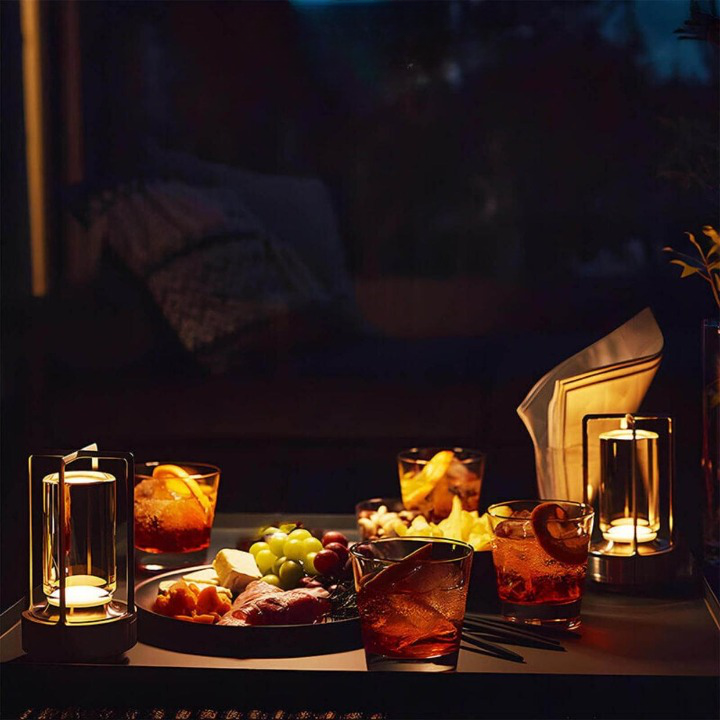 Deux lampes allumées sur une table basse avec cocktails, planche de fruits et charcuterie pour un apéritif en soirée. 6