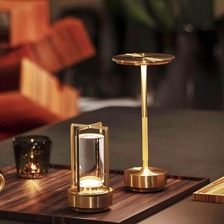 Lampe dorée à cadre ouvert posée près d'une lampe de table dorée à tige fine, sur un plateau en bois. 7