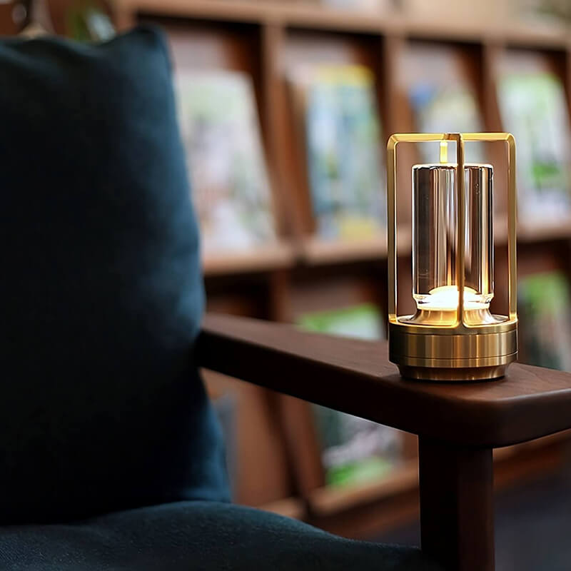 Lampe dorée allumée sur l'accoudoir en bois d'un fauteuil bleu foncé, avec une bibliothèque floue en arrière-plan. 8