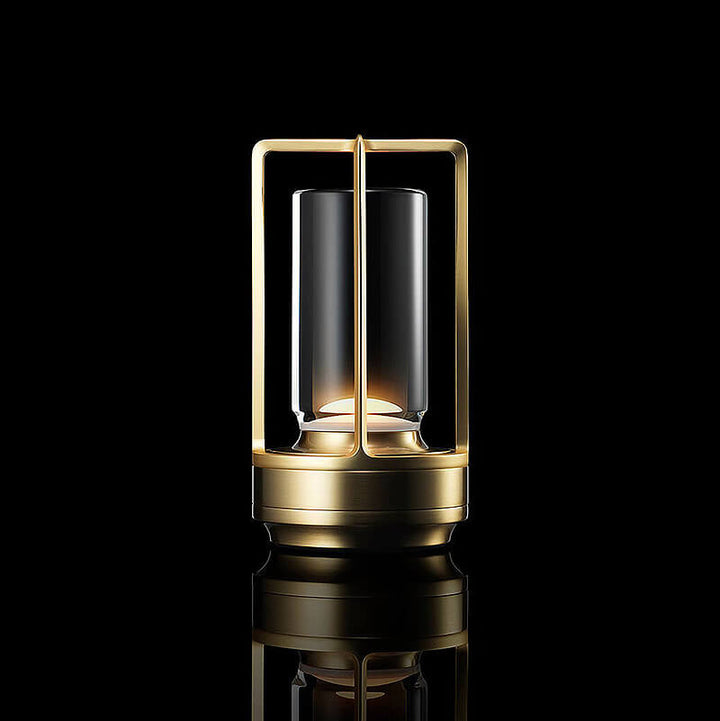 Lampe cylindrique à cadre ouvert doré et base en laiton, allumée sur fond noir avec reflet au sol. 1
