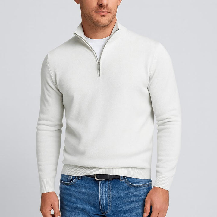 Pull blanc cassé à col zippé porté avec un jean et une ceinture noire, vue de face sur fond gris clair. 2