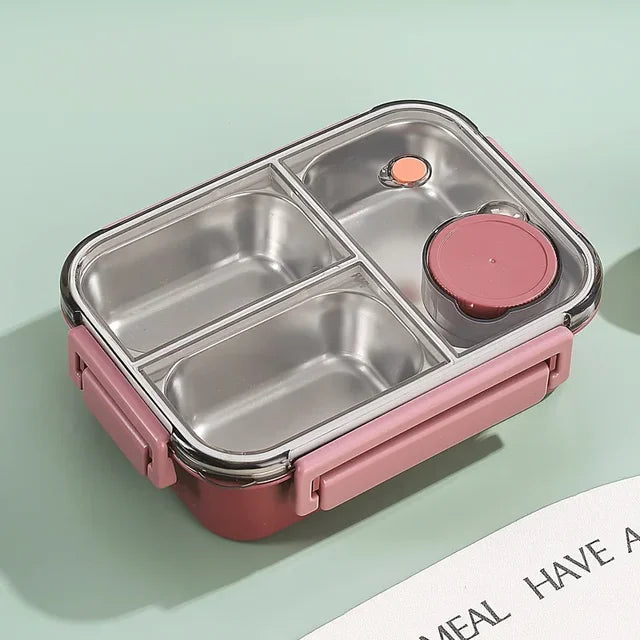 Boîte repas rose vide, couvercle transparent fermé sur trois compartiments en inox, avec petit pot rond rose et deux fermoirs latéraux. 14
